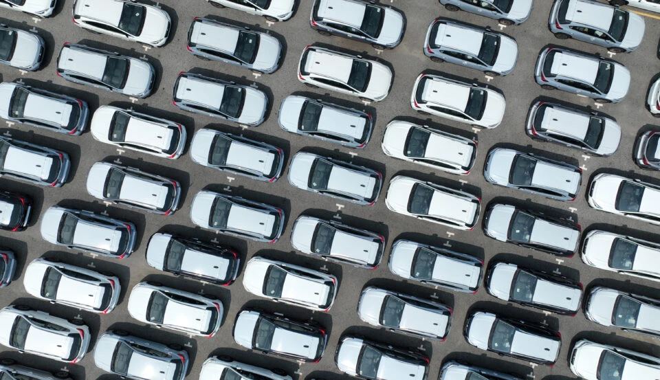 aerial view of a parking lot full of identical white cars, illustrating the baader-meinhof phenomenon, where you buy a car and start seeing it everywhere.