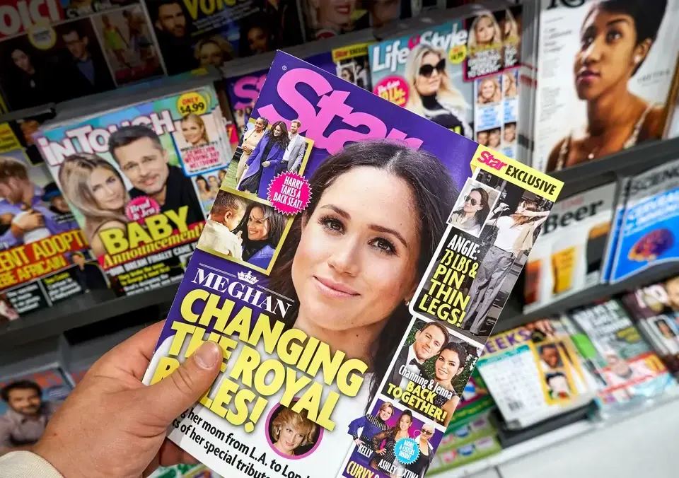 A hand holds a Star magazine featuring Meghan Markle, surrounded by other celebrity magazines. This illustrates the importance of choosing how many SEO keywords to use for impactful headlines.