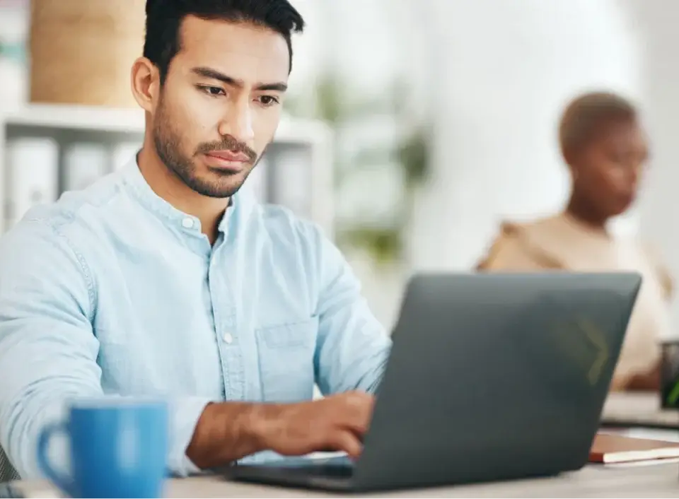 Focused man typing on a laptop in an office, researching effective on page SEO services for businesses.