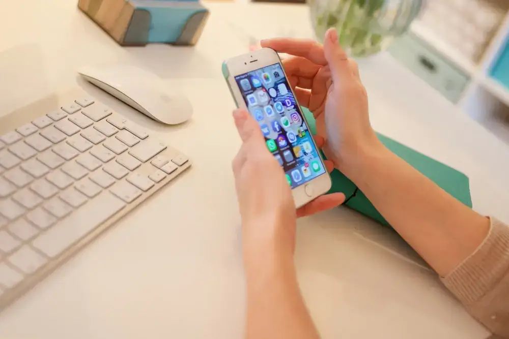A hand holding a smartphone with PPC ad results displayed, surrounded by floating dollar signs, emphasizing the benefits of investing in PPC services