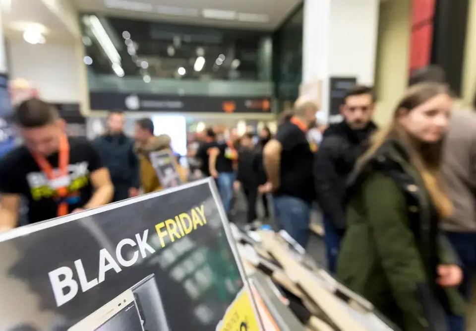 Crowd of shoppers in a store with a 'Black Friday' sign in the foreground, demonstrating scarcity marketing.