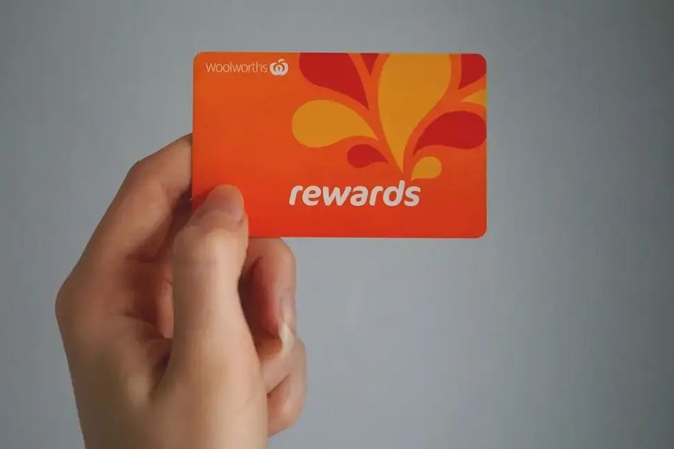 Hand holding an orange Woolworths Rewards card, a key strategy to increase customer lifetime value through loyalty programs.