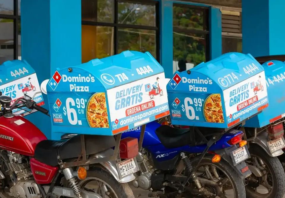 Domino's Pizza delivery motorcycles with blue boxes showing a $6.99 pizza deal, illustrating the psychology of pricing.