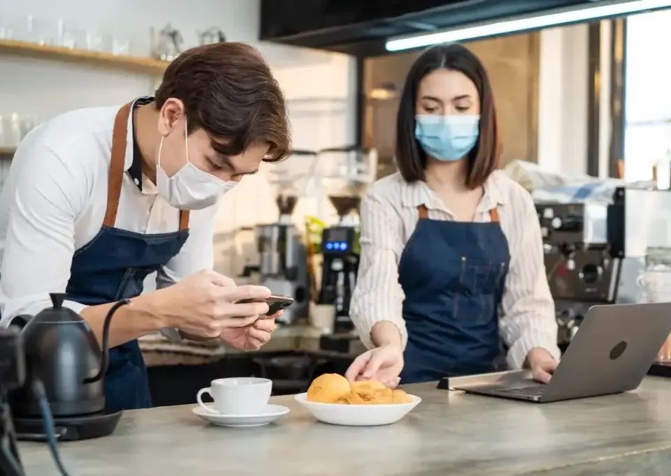 Barista checking digital marketing analytics on smartphone to understand what CPA is in café setting.
