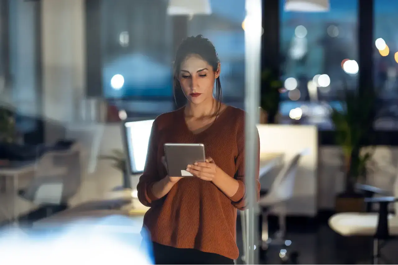 A person uses a tablet to outline a digital marketing strategy, with a cityscape glowing in the background, signifying modern business growth