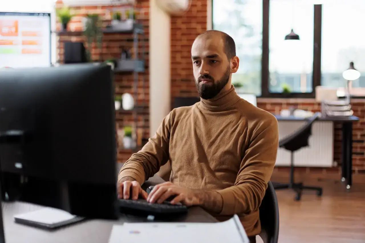 A diverse team of professionals collaboratively working on computers and tablets in a modern office, representing a digital marketing agency