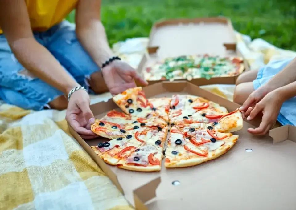 Two people sharing a pizza on a checkered blanket, illustrating collaborative fractional leadership.
