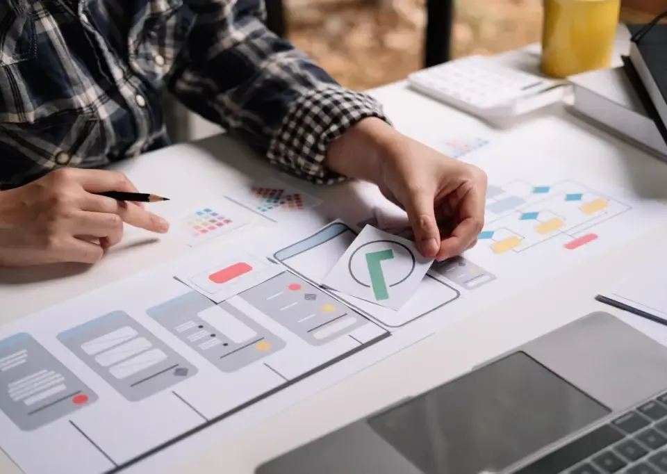 Designer creating a user interface with wireframes and color swatches, illustrating the primacy effect in design.
