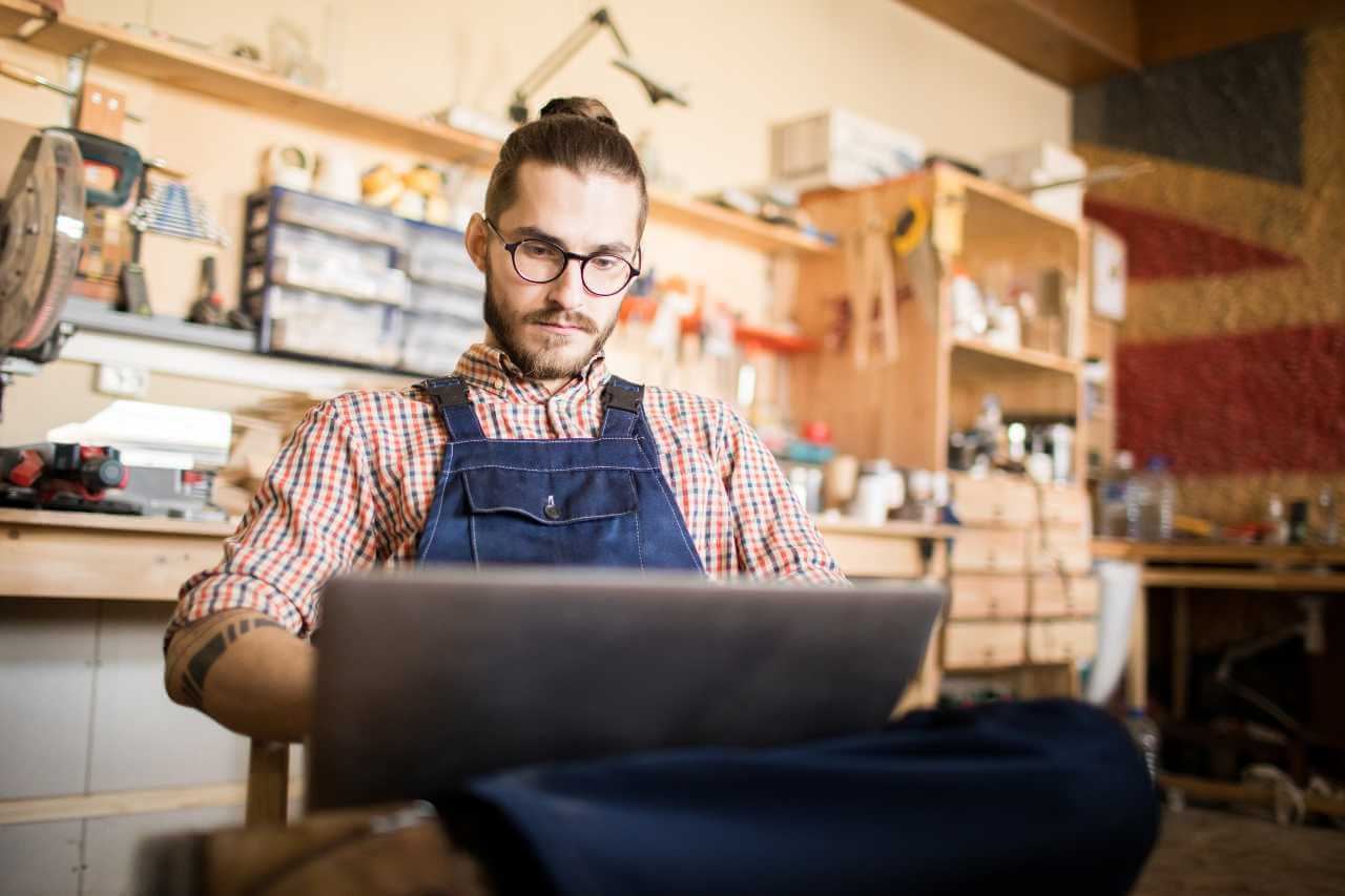 A small business owner happily points at a laptop displaying a Google Ads dashboard, signifying worth for small businesses