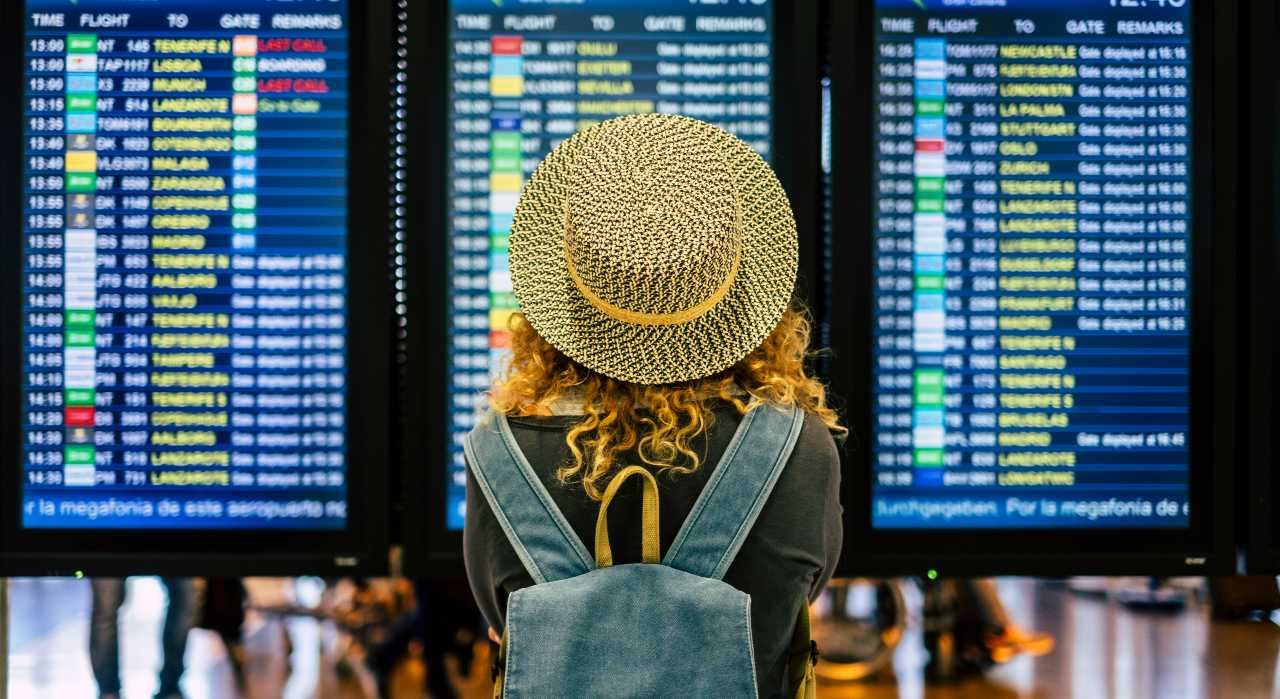 A person's hand reaches out to touch a large, glowing Google Travel icon, representing big questions about its search ads